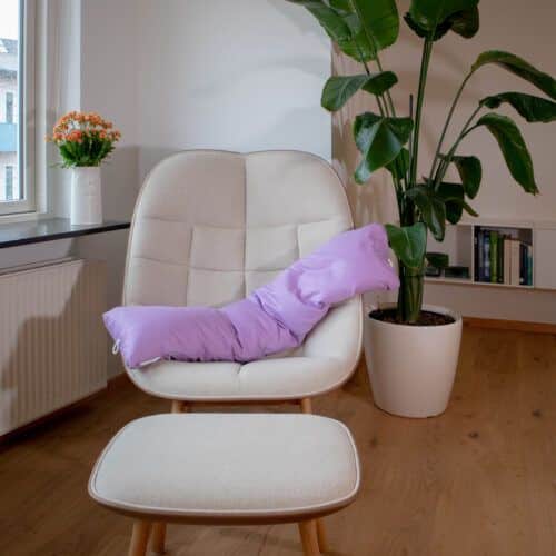 Graviditets- og ammepude fra B'Comphy (130 cm) lavendel i en stol