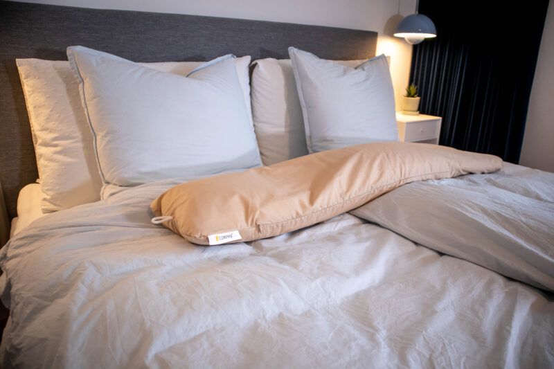 Graviditets- og ammepude fra B'Comphy (130 cm) cappuccino i en seng